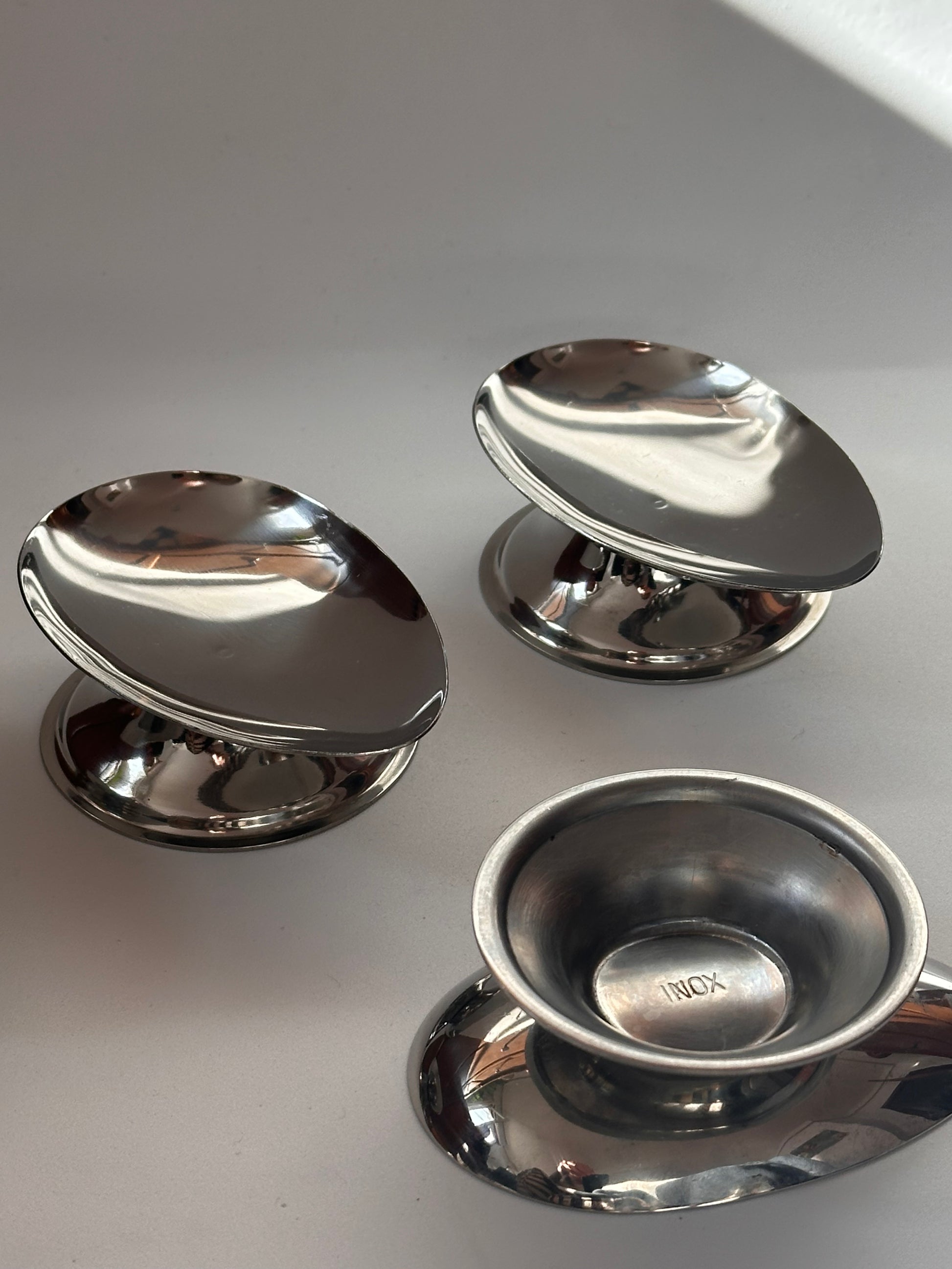 Three minimalistic silver stainless steel dishes with polished finish, designed for serving avocado.